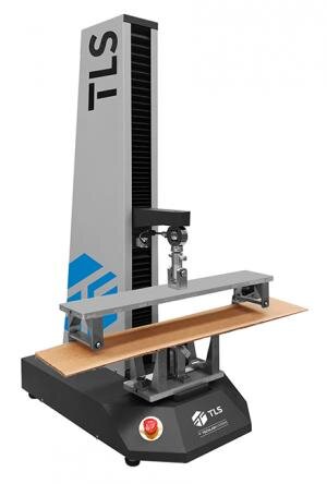 Zdjęcie ukazujące aparat do mierzenia odporności na przebicie. Podstawa urządzenia stoi na czterech gumowych podpórkach, na niej zamontowany jest trójkątny wyciąg, do którego, na wybranej wysokości, mocuje się ramię. Z ramienia zwisa para prostokątnych, poziomych płyt do umieszczania próbek.