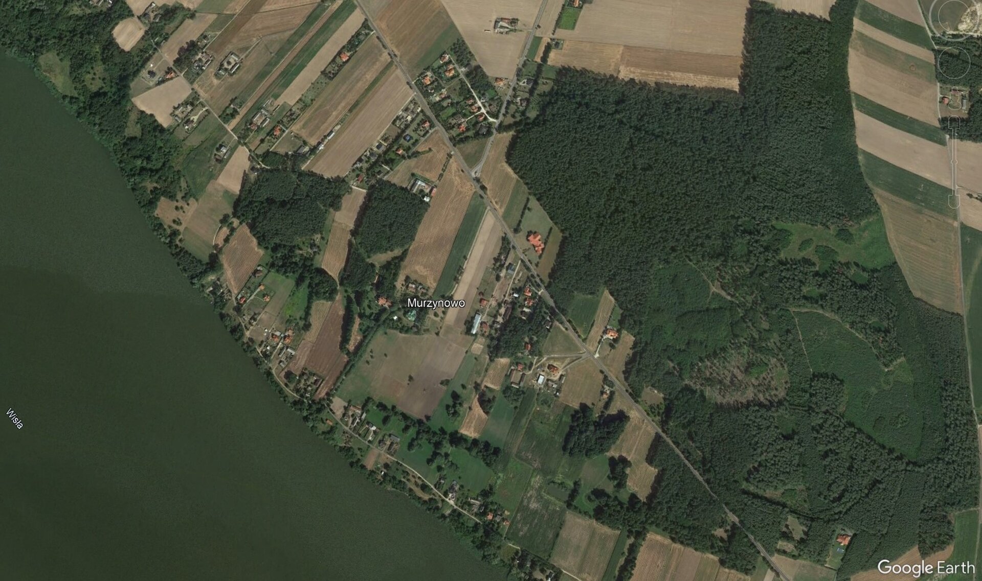 Zdjęcie satelitarne. Na nim w lewym dolnym rogu rzeka, na jej brzegach drzewa. W sąsiedztwie rzeki pola uprawne ułożone szachownicowo.