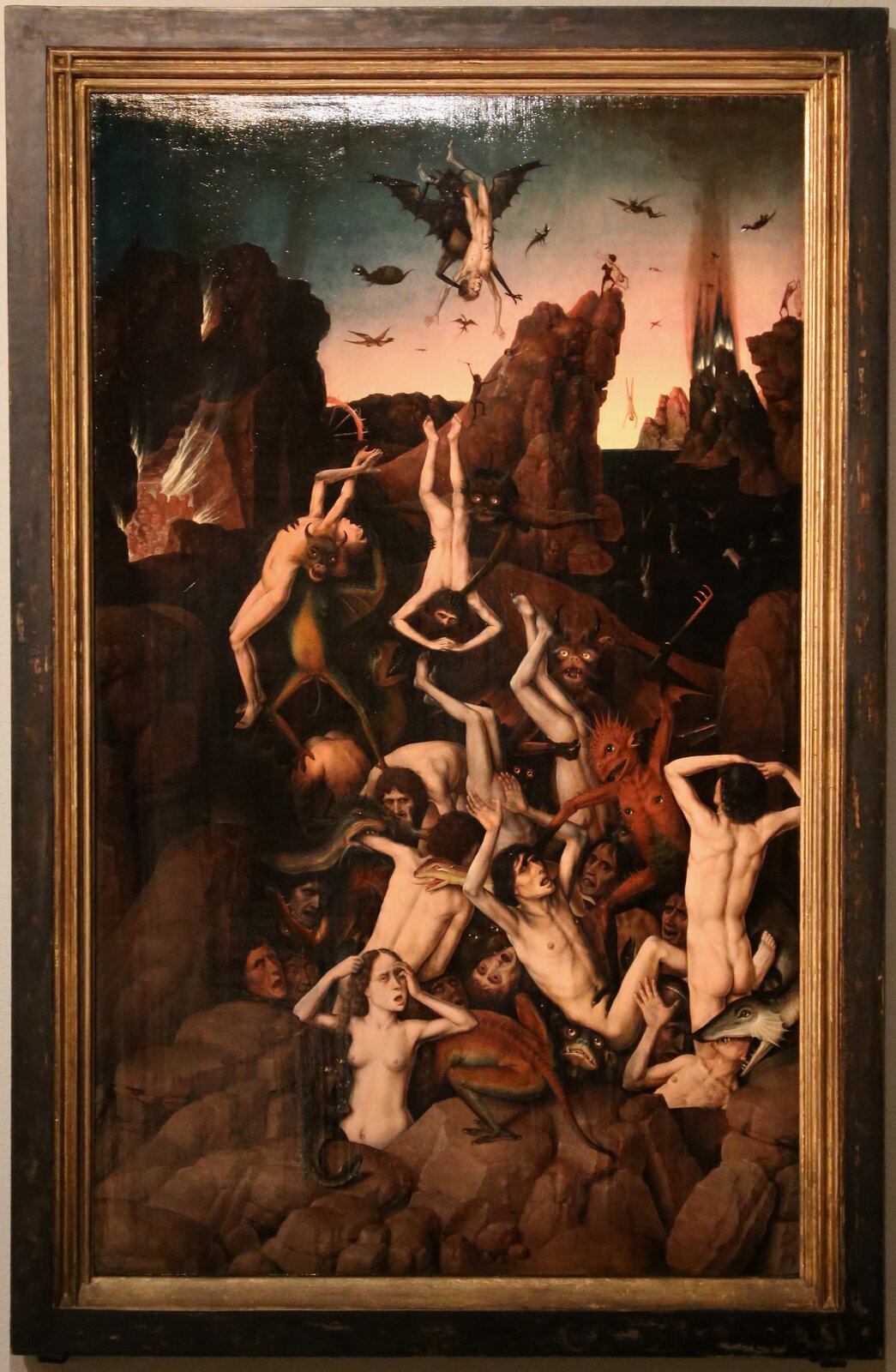 Obraz przedstawia skaliste piekło. Nadzy ludzie są dręczeni przez stwory o różnych kształtach. Są to między innymi człekokształtne gady i ryba. Po lewej stronie jest płonąca jaskinia, w której znajduje się grupa ludzi. Po niebie latają stwory ze skrzydłami. Jeden z nich trzyma człowieka do góry nogami. W tle są wysokie klify, z których są zrzucani ludzie. Dalej są buchające płomienie i unoszący się dym.