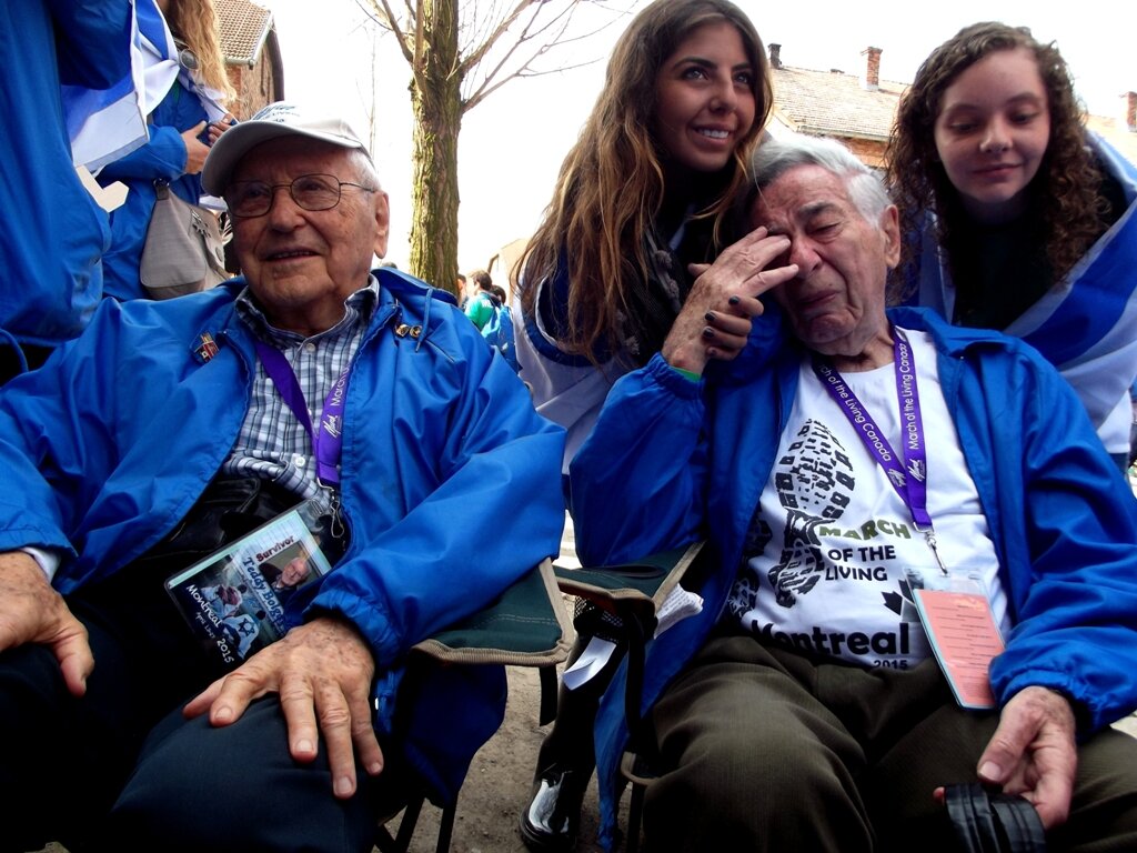 Fotografia barwna przedstawia uczestników Marszu Żywych. Na pierwszym planie byli więźniowie  Auschwitz, z tyłu młodzi uczestnicy marszu.