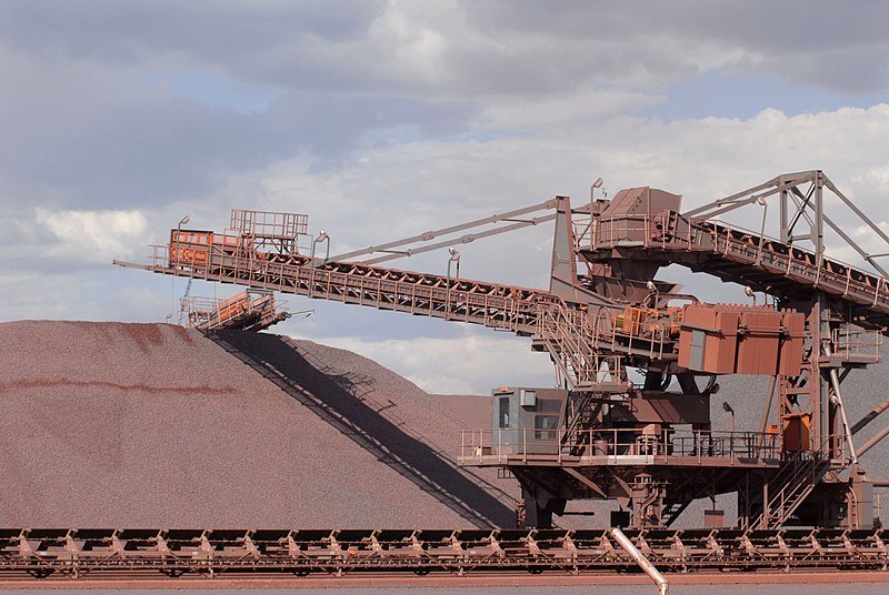 Na zdjęciu widać pracującą zwałowarkę. Po lewej stronie zdjęcia widać hałdę surowca. Hałda ma kształt piramidy. Po prawej stronie hałdy znajduje się zwałowarka. Zwałowarka jest dużą maszyną poruszającą się po torach. W górnej części zwałowarki znajduje się wysunięte ramię na którym zamontowany jest przenośnik taśmowy. Z przenośnika na hałdę spada transportowany surowiec.