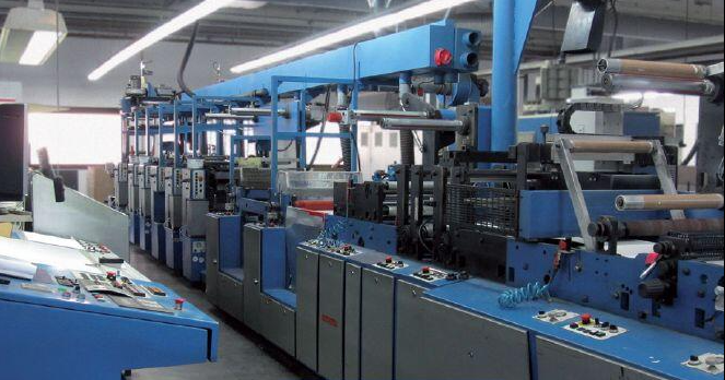 Zdjęcie przedstawia prasę rotacyjną. Jest to duże wieloelementowe urządzenie. Posiada liczne przyciski. Widoczne są też rolki.