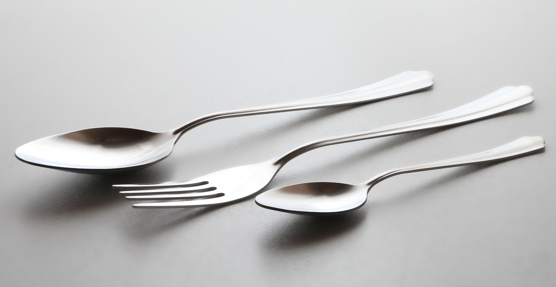 Zdjęcie przedstawia sztućce: łyżkę, widelec i łyżeczkę.