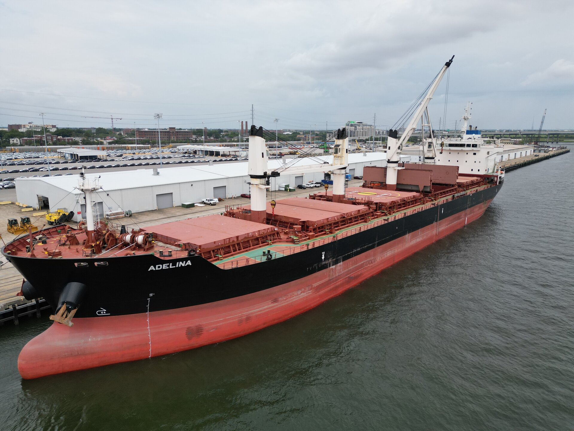 Zdjęcie przedstawia statek zbiornikowiec zacumowany w porcie. Posiada on pięć dużych zbiorników z prostokątnymi pokrywami oraz dźwigiem. Drugi od rufy zbiornik jest otwarty.