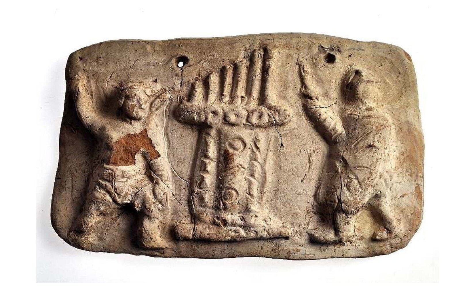 Na zdjęciu zaprezentowany został fragment kamienia w beżowym kolorze, w którym to wyrzeźbione zostały dwie postacie o zamazanych konturach, a pośrodku nich wykute zostały organy wodne dużych rozmiarów, zbliżone wielkością do ludzi.