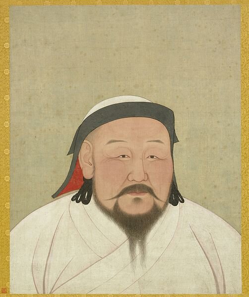Na ilustracji przedstawiono mężczyznę w średnim wieku. Ma on skośne oczy, wąsko zakończone wąsy oraz dłuższą, rozdwojoną brodę. Ma pucułowatą twarz i włosy do ramion. Ubrany jest w białą szatę i czapkę
