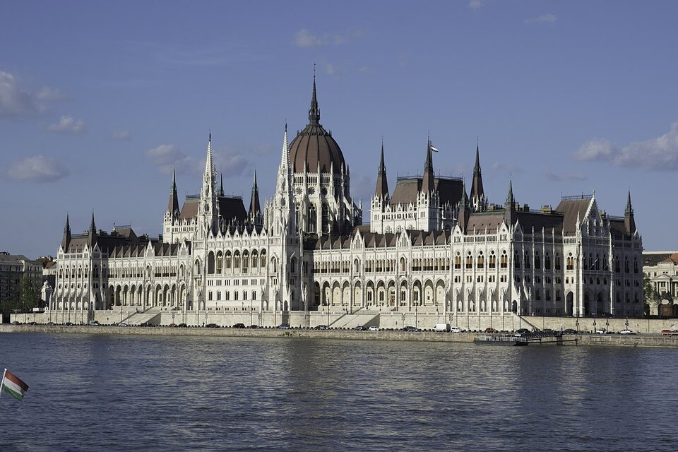 Na zdjęciu budynek parlamentu. Składa się z kilku strzelistych wież oraz środkowej części zwieńczonej kopułą. Budynek położony jest nad rzeką. 
