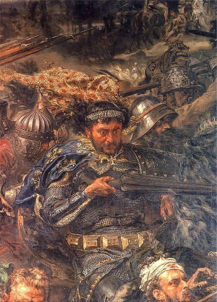 Fragment obrazu. W centrum kompozycji widoczny jest mężczyzna w bogato zdobionej zbroi, który trzyma w rękach miecz i z wyrazem determinacji na twarzy uczestniczy w walce. Jego postać wyróżnia się na tle innych wojowników dzięki szczegółowemu przedstawieniu twarzy, elementów pancerza oraz ozdobnego pasa. W tle widoczne są inne postacie rycerzy – w hełmach, zbrojach i z bronią, oddające intensywność starcia.
Scena pełna jest ruchu, napięcia i dramatyzmu, oddanych poprzez gesty postaci, napięte mięśnie, dynamiczne pozy oraz wielość szczegółów. Przeważają ciemne, nasycone barwy z mocnymi światłocieniami.
