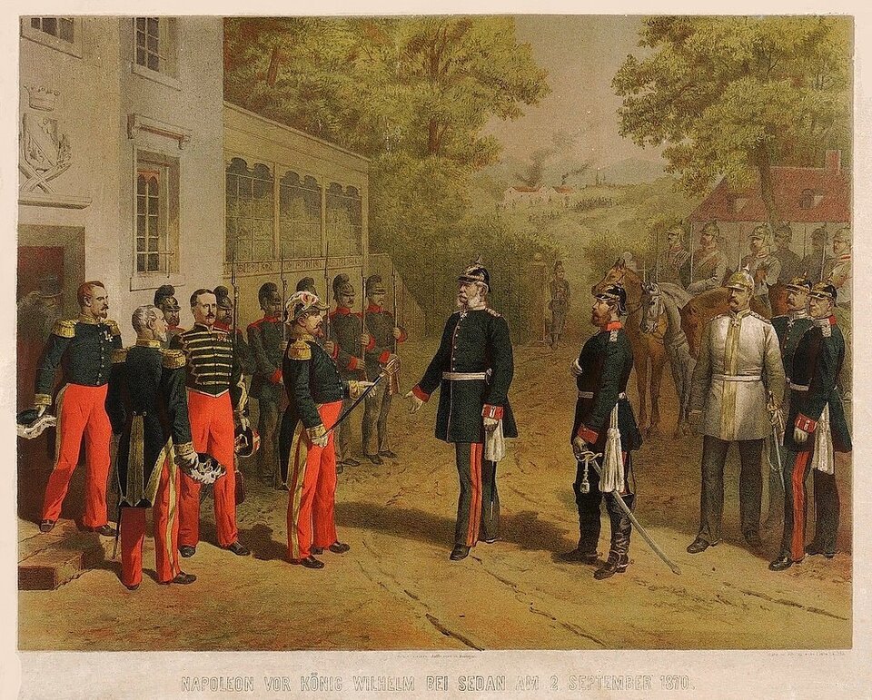 Obraz przedstawia Napoleona trzeciego kapitulującego przed królem Prus. Napoleon wraz z swoją świta jest ubrany w ciemny mundur i czerwone spodnie. Wręcza królowi Prus szablę. Za królem stoją i siedzą na koniach pruscy oficerowie. W oddali znajdują się zabudowania i liczne drzewa. 