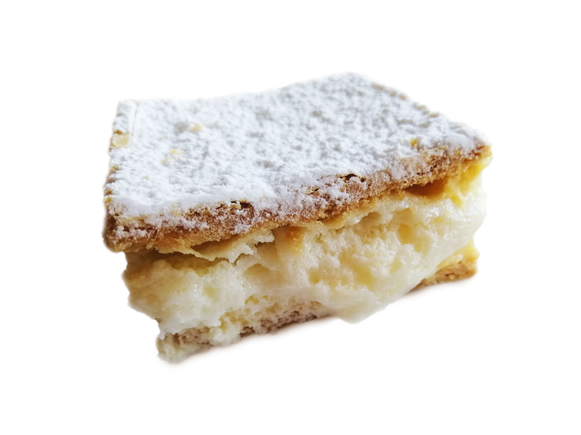 Kostka ciasta z kremem, na górze posypana cukrem pudrem. Krem wylewa się z ciasta.
