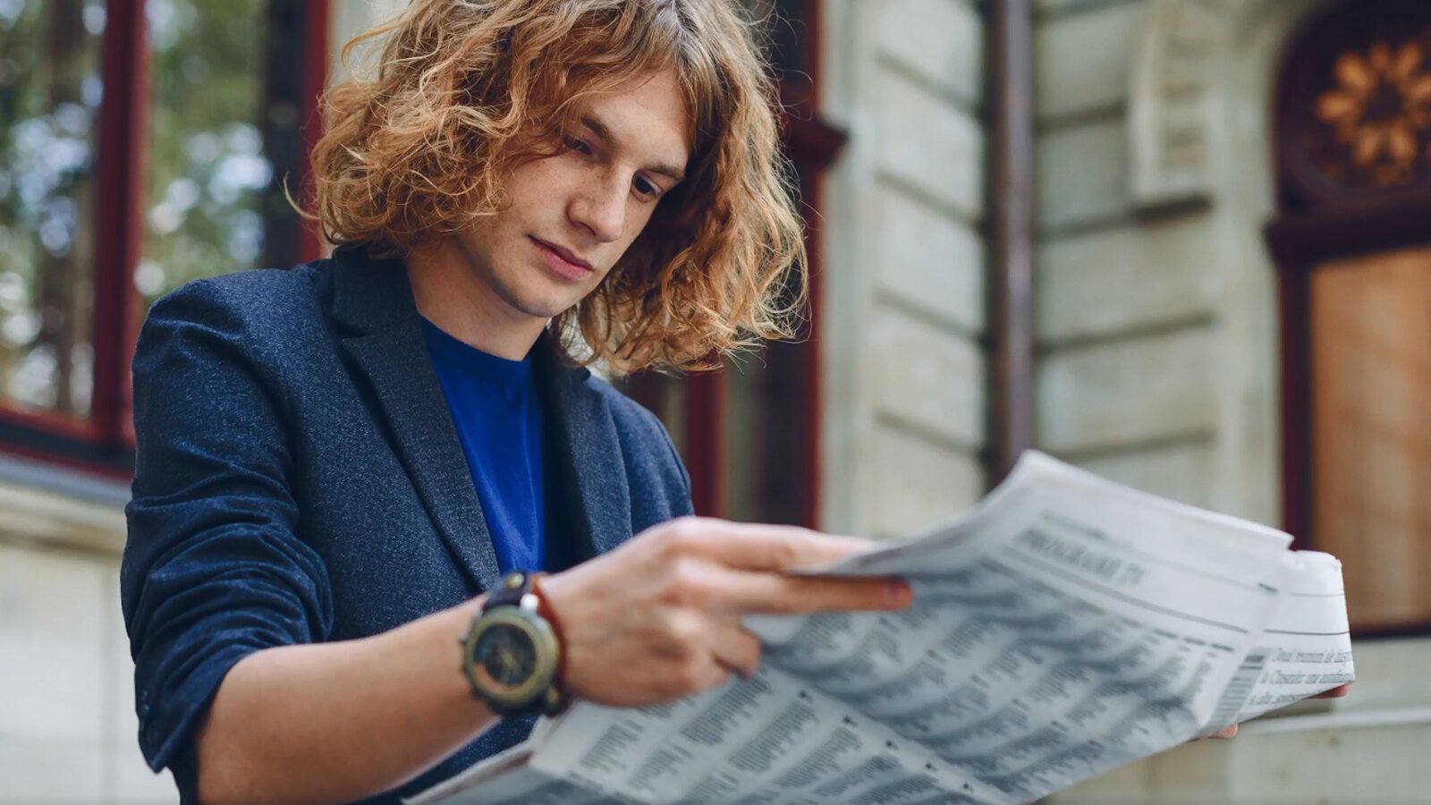 Ilustracja prezentuje młodego mężczyznę czytającego gazetę. 