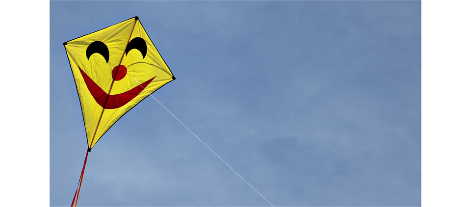 Na ilustracji przedstawiono latawiec z usmiechniętą buźką, na tle nieba.