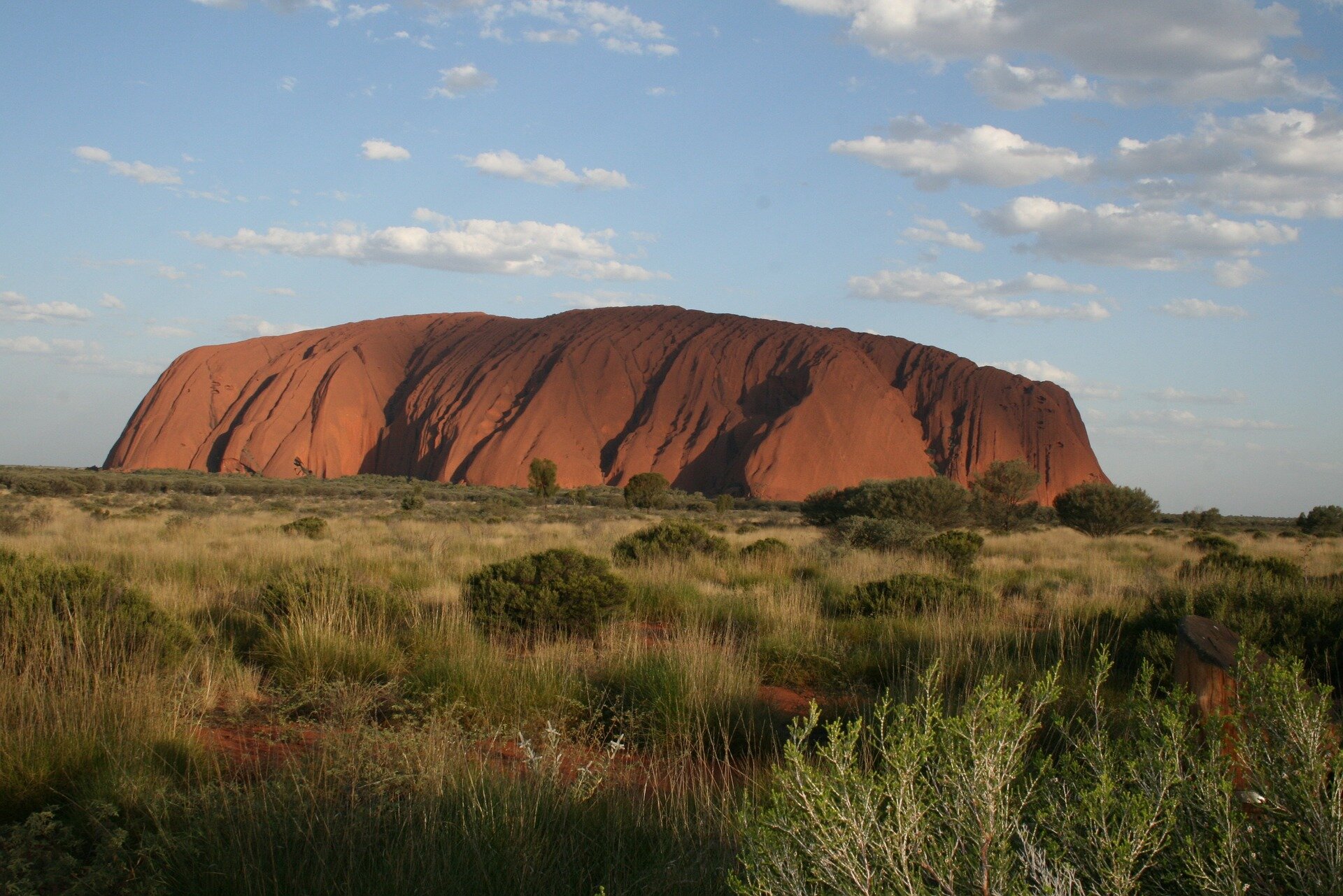 Fotografia barwna przedstawiająca Uluru, Oolora – formację skalną w centralnej części Australii, na Terytorium Północnym. Skała ma zabarwienie czerwone.