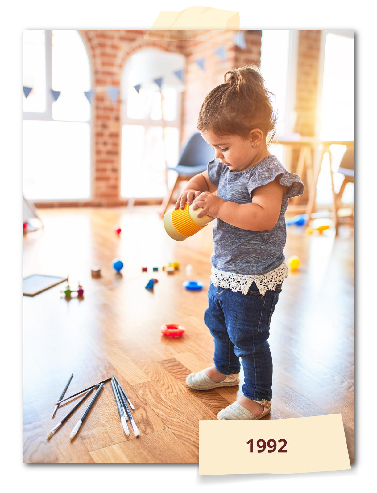 Ilustracja przedstawia dziewczynkę w pomieszczeniu bawiącą się zabawką. Na podłodze leżą pędzle i inne zabawki. Rok: 1992.