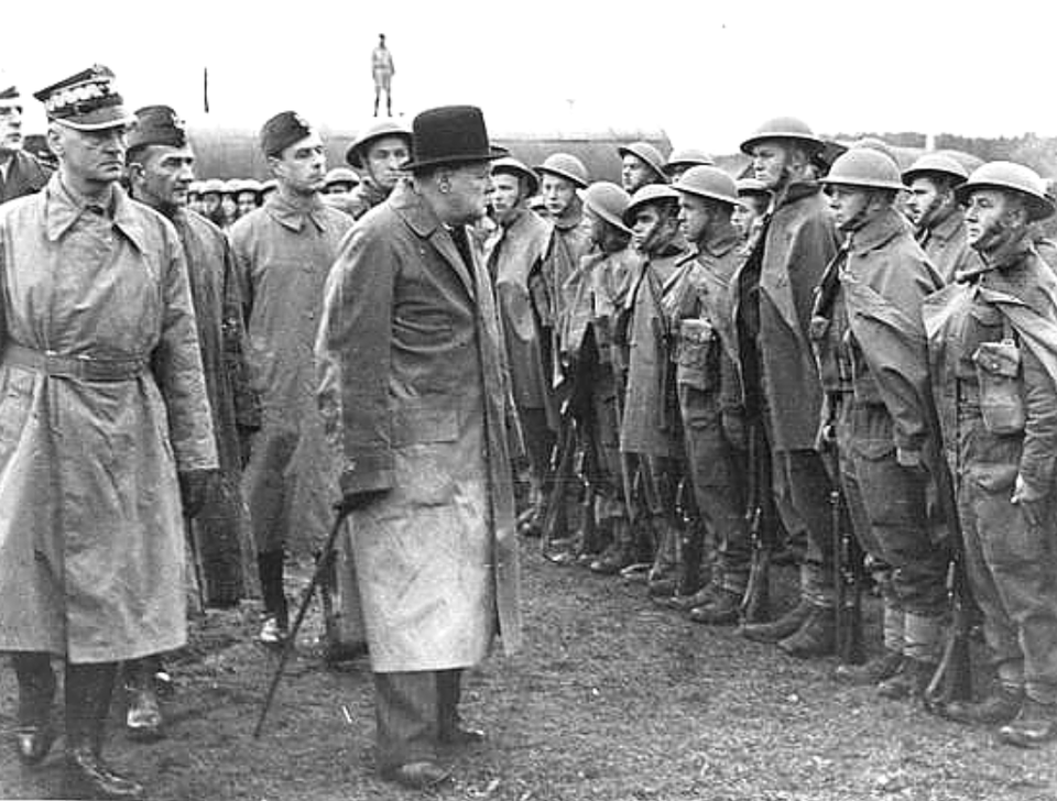 Czarno‑biała fotografia przedstawia Winstona Churchilla wizytującego w towarzystwie generała Władysława Sikorskiego jednostkę Polskich Sił Zbrojnych na Zachodzie. Churchill przedstawiony jest w centralnej części fotografii. Jest to mężczyzna dość niski, na głowie ma czarny cylinder. Ubrany jest w długi płaszcz, spod którego wystają szerokie, ciemne nogawki spodni, w ręce trzyma laskę. Za Churchillem stoi generał Sikorski. Na głowie ma czapkę z daszkiem, ubrany jest w długi płaszcz. Obok Sikorskiego stoją jego polscy współpracownicy w mundurach wojskowych i czapkach furażerkach. Wizytowani polscy żołnierze stoją naprzeciwko Churchilla w szeregu, na głowie mają okrągłe hełmy z wąskim rondem zapinane pod brodą. Ubrani są w kombinezony i ciemne buty.