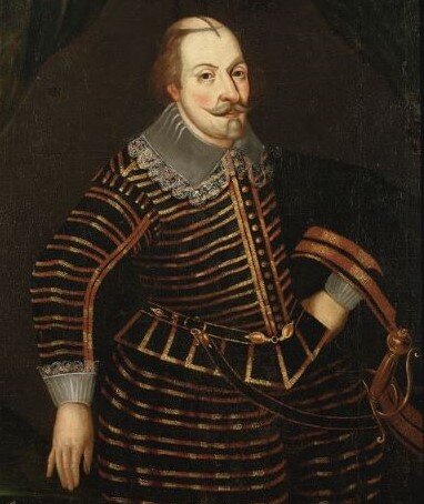 Ilustracja przedstawia Karola Sudermańskiego. Na czubku głowy nie ma włosów jednak z tyłu głowy ma brązowe. Ma też wąsy. Przy szyi ma szary kołnierz obszyty koronką. Jego szata jest czarna w złote poziome paski. Przy dłoniach też ma koronkę. Na lewym ramieniu zwisa czarny płaszcz. U pasa jest przypięty miecz.