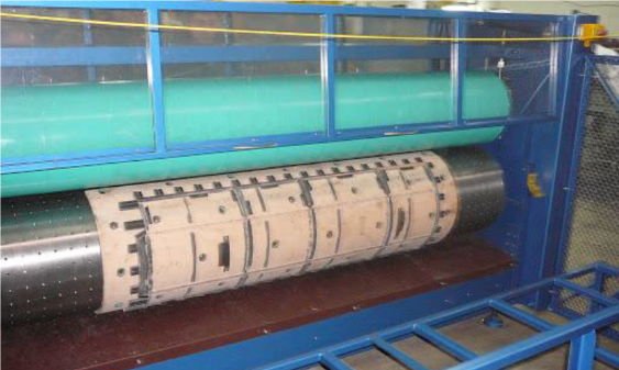 Zdjęcie przedstawia wykrojnik rotacyjny. Składa się z dwóch wałków, z czego niższy posiada wypustki.