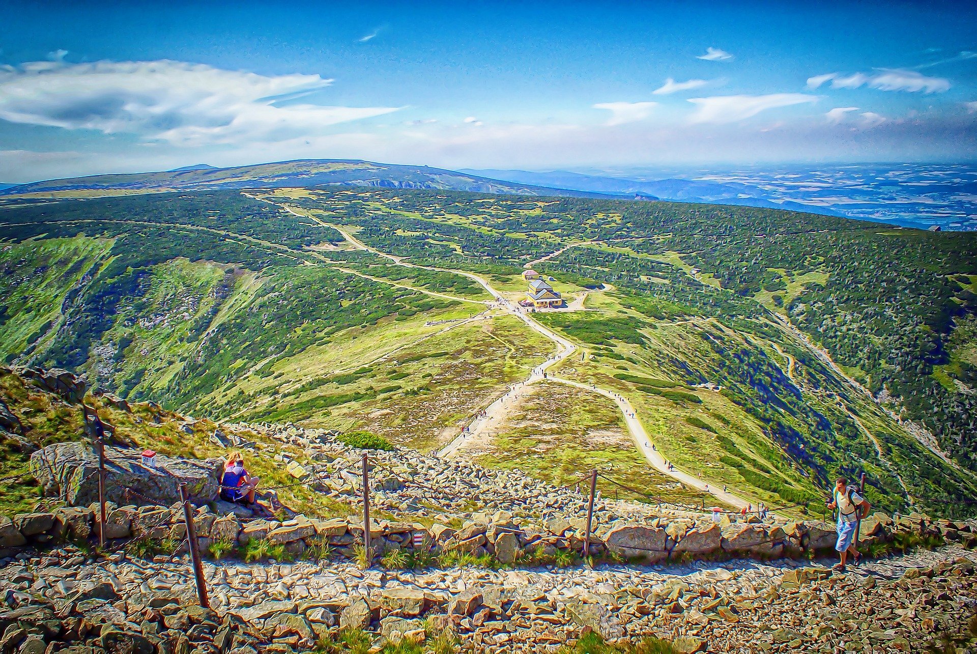 Zdjęcie przedstawia górskie szlaki, biegnące po łagodnych, porośniętych roślinnością wzniesieniach.    