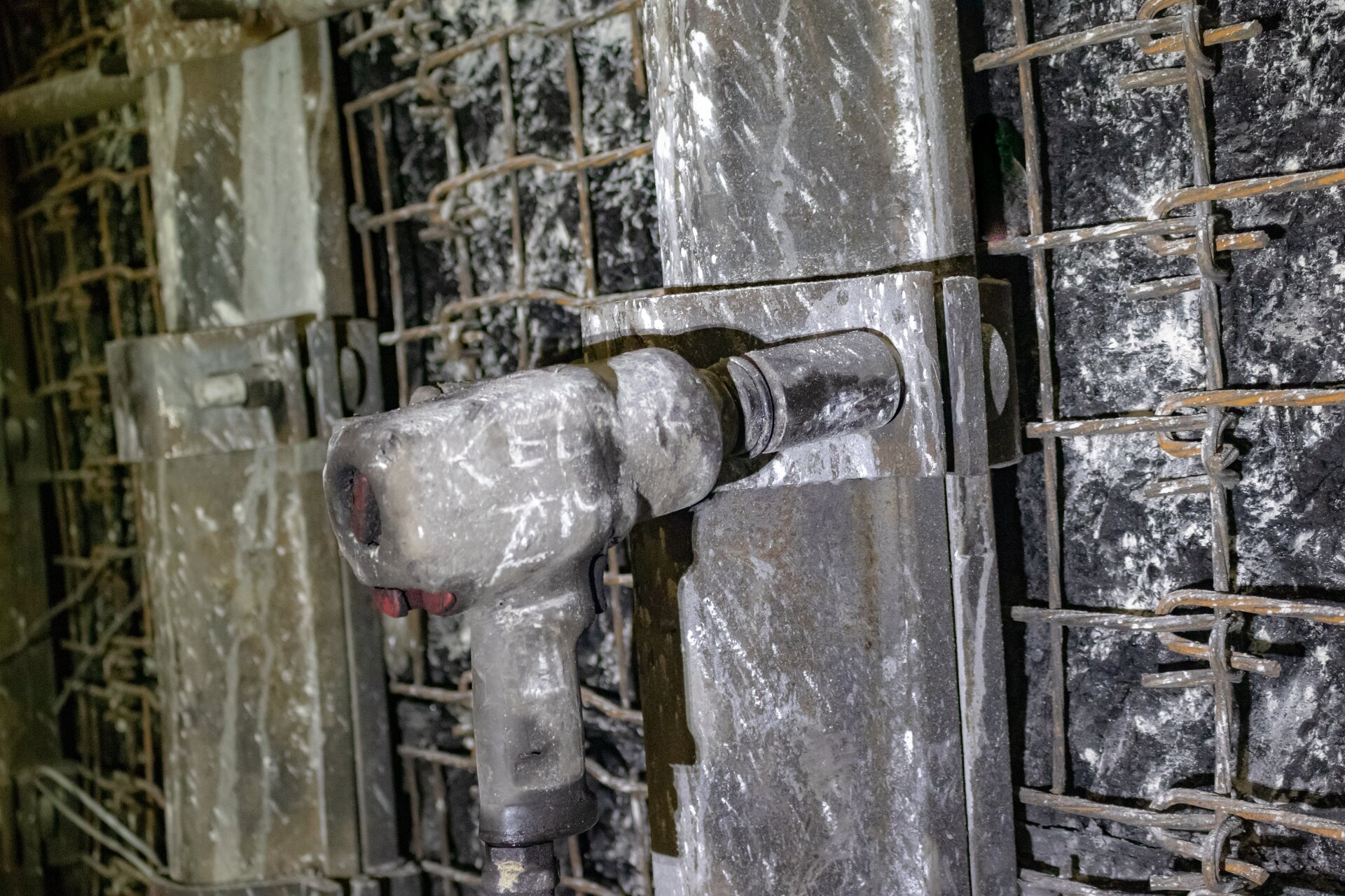 Na zdjęciu widoczny jest klucz pneumatyczny. Klucz przypomina kształtem pistolet. Różnicę z pistoletem stanowi organ roboczy. Lufa klucza jest o kształcie cylindra na który założony jest klucz nasadowy. Klucz nasadowy jest o kształcie cylindra. Klucz ten nakłada się na śrubę.Widoczny na zdjęciu klucz jest nałożony na śrubę obejmy obudowy. W tle widać zabezpieczony ocios wyrobiska.