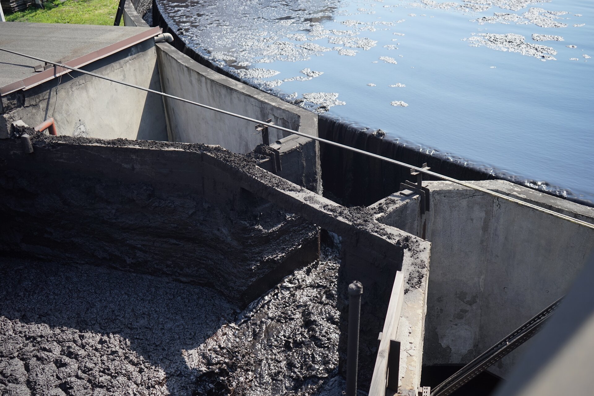 Zdjęcie przedstawia fragment pierścieniowatej rynny przelewowej zagęszczacza promieniowego. Kierowana jest nią do odpływu woda klarowna. Poniżej znajduje się zbiornik z zagęszczonym mułem. Poniżej zdjęcia znajduje się przycisk multimedialny z nagraniem audio. Treść nagrania jest zgodna z tytułem zdjęcia.