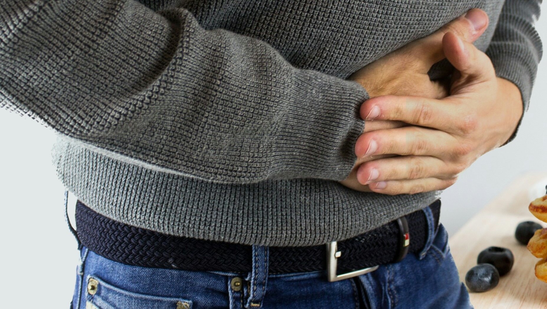 Ilustracja przedstawia mężczyznę trzymającego się za brzuch.