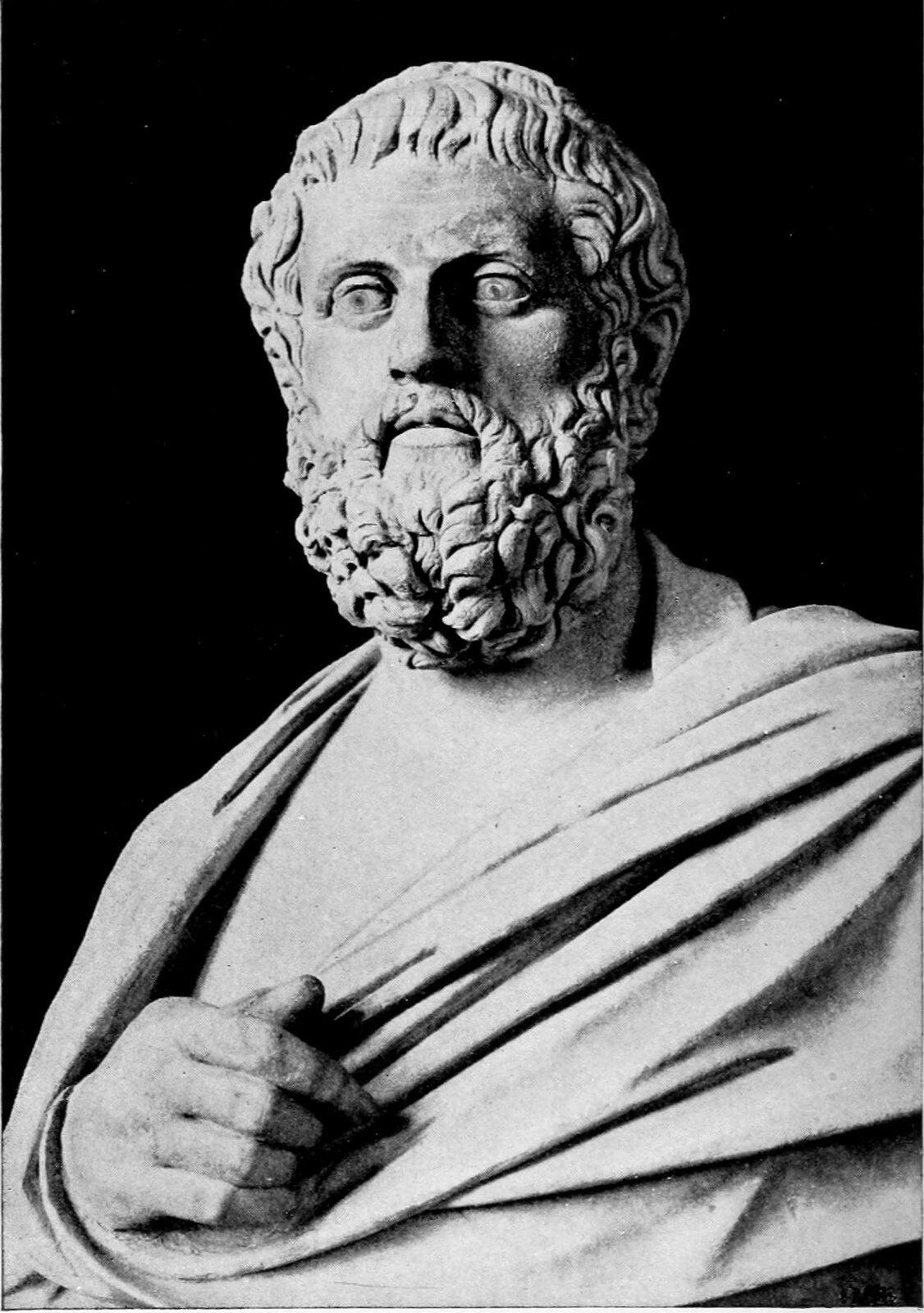 Zdjęcie przedstawia posąg — popiersie Sofoklesa. Mężczyzna jest w dojrzałym wieku. Ma falowane, średniej długości włosy i gęstą brodę. Na ramionach ma zarzuconą togę. Wystaje spod niej prawa ręka.