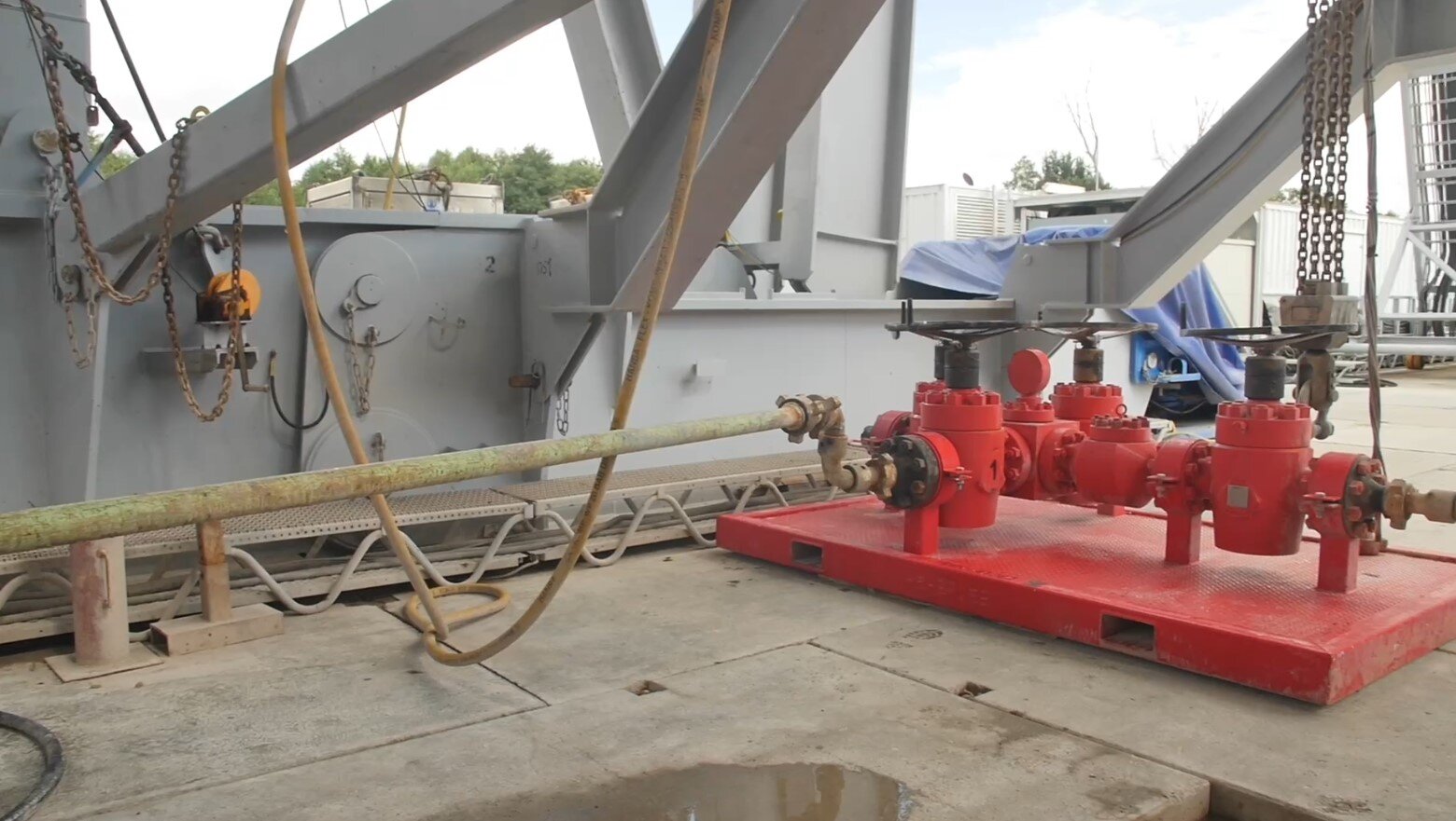 Na zdjęciu widoczny jest węzeł zatłaczania. Węzeł zatłaczania służy do zatłaczania płuczki. Jest to platforma, na której znajdują się przewody oraz zawory. Do platformy, z lewej strony, podłączony jest przewód.Poniżej zdjęcia w prawym dolnym rogu widoczny jest przycisk odtwarzania. Tekst nagrania jest zgodny z tytułem zdjęcia.