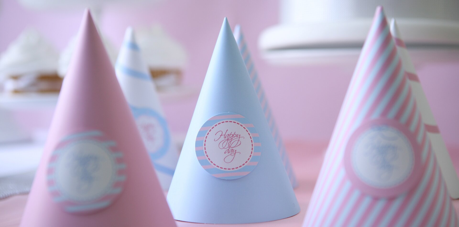 Zdjęcie sześciu kolorowych czapeczek w kształcie stożków przeznaczonych dla gości. Na każdej z nich umieszczono okrągłą nalepkę z napisem: Happy Day. 