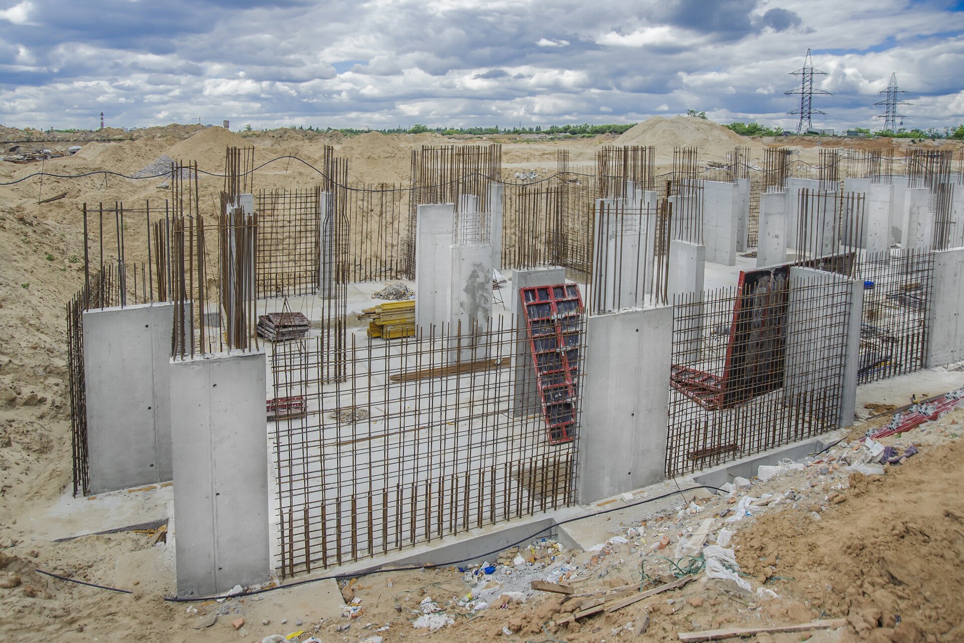 Zdjęcie przedstawia zbrojenie ścian wznoszonego budynku. Dookoła widać zaspy piasku.