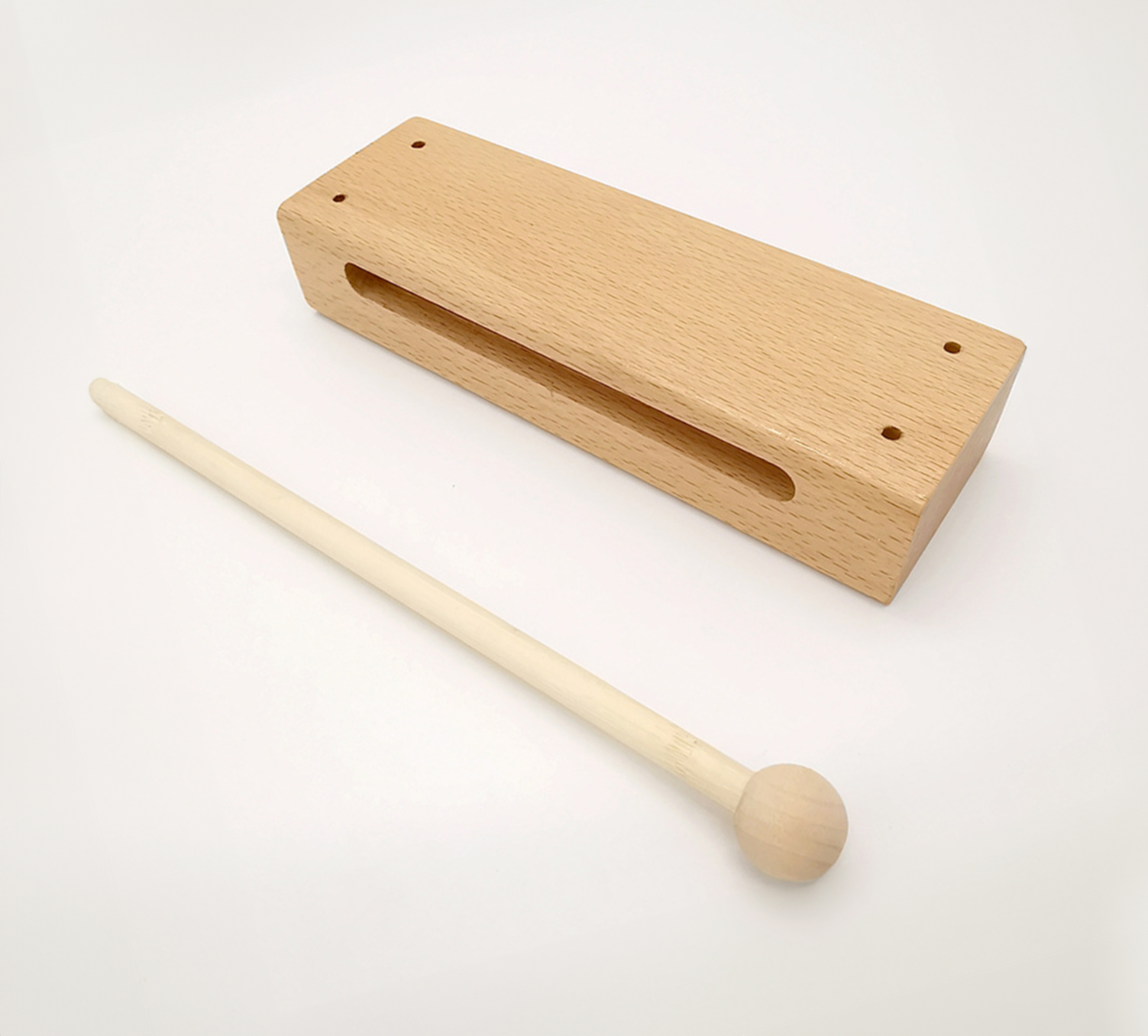 Zdjęcie przedstawia pudełko akustyczne. Jest to instrument w postaci prostokątnego drewnianego pudełka pustego w środku. Do instrumentu jest dołączona drewniana pałeczka służąca do uderzania w pudełko.