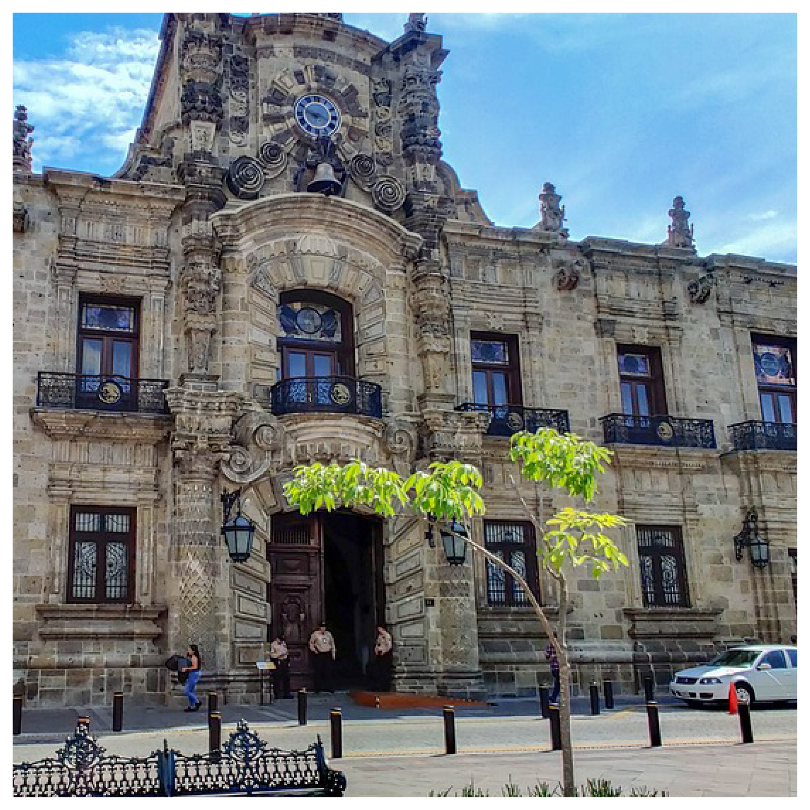 Zdjęcie przedstawia duży budynek z beżowych cegieł z ratuszem po środku.