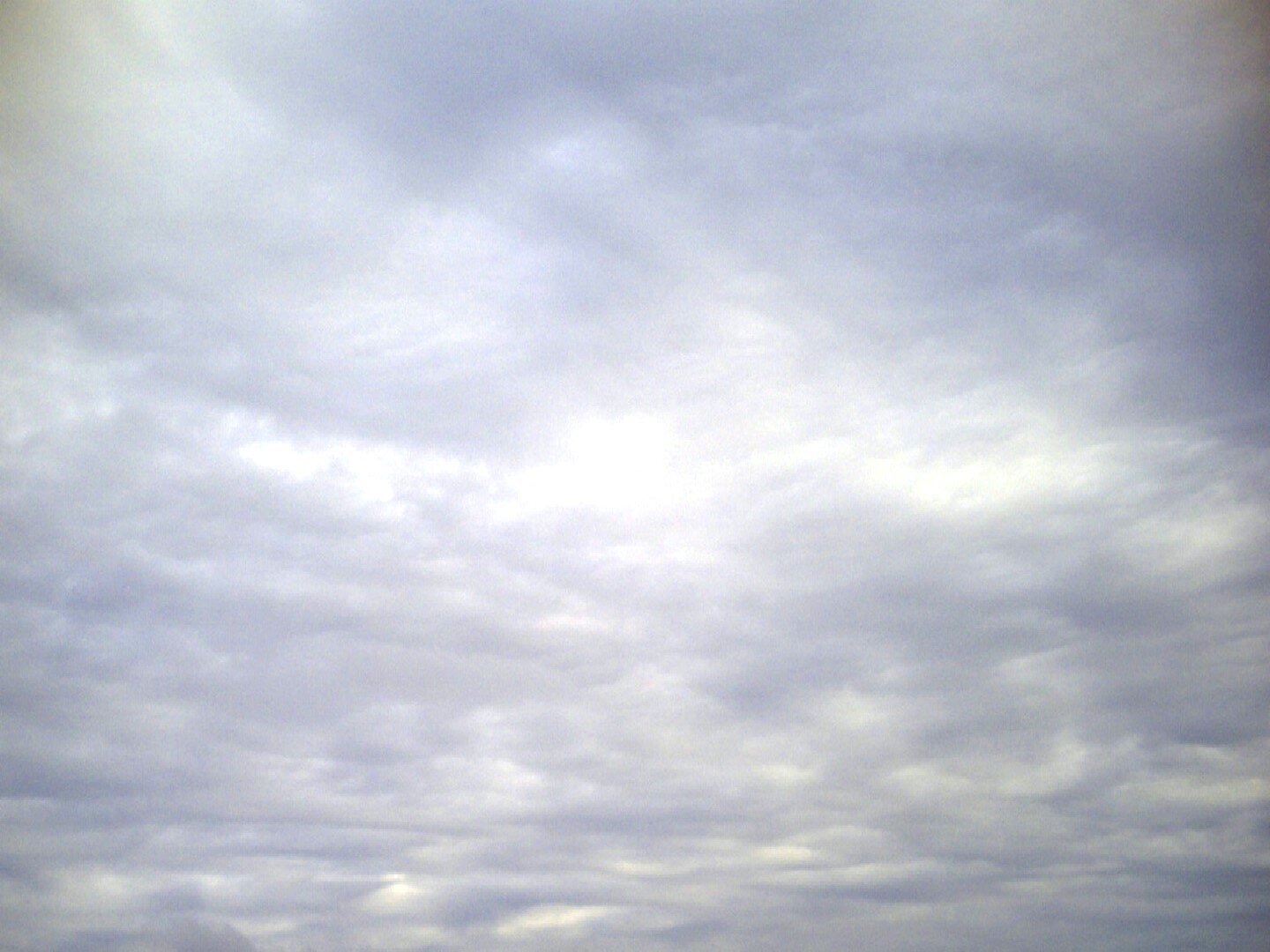 Fotografia przedstawia fragment nieba pokrytego popielatowymi chmurami przypominającymi kożuch.