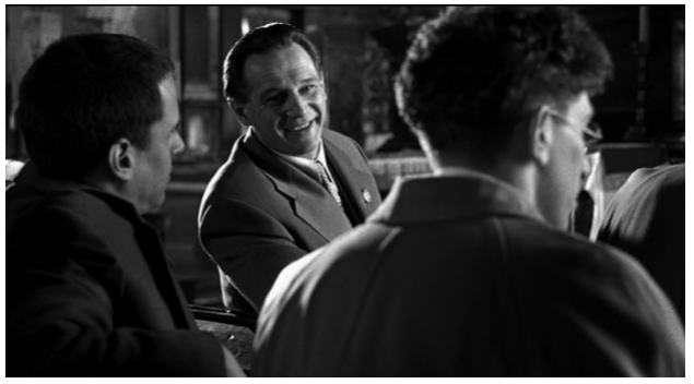 Zdjęcie przedstawia wnętrze kościoła. Siedzą w nim w ławkach trzej mężczyźni. Jednym z nich jest Schindler . Mężczyźni rozmawiają, Schindler się śmieje.