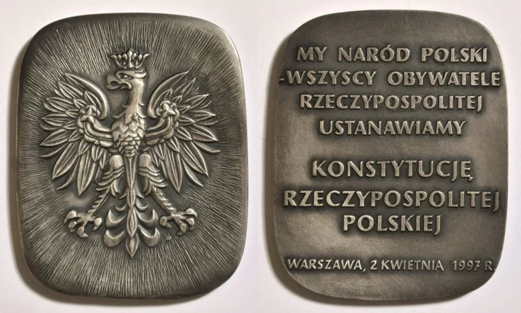 Ilustracja przedstawia medal okolicznościowy upamiętniający Konstytucję Rzeczypospolitej Polskiej. Po jednej stronie medalu znajduje się orzeł w koronie, po drugiej stronie medalu znajduje się napis: My naród polski – wszyscy obywatele Rzeczypospolitej ustanawiamy Konstytucję Rzeczypospolitej Polskiej. Warszawa, 2 kwietnia 1997 r. 
