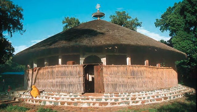 Zdjęcie przedstawia okrągły szałas pokryty strzechą.