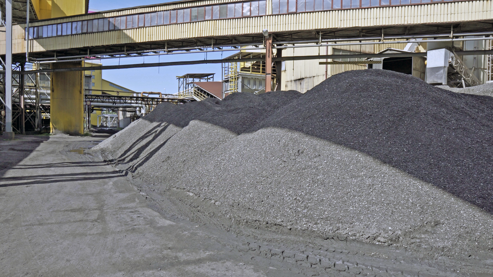 Na zdjęciu widoczne jest składowisko z węglem. Widoczne na zdjęciu zwały mają kształt pryzm. Za pryzmami widoczny jest podwieszony przenośnik taśmowy. Budynek przypomina cienki prostopadłościan. W tle znajdują się budynki przemysłowe.