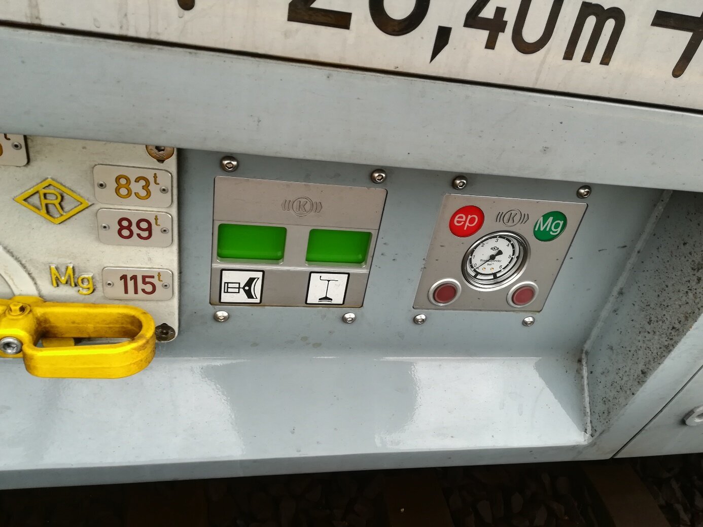 Zdjęcie przedstawia wskaźnik hamulca tarczowego. Na zdjęciu pokazany jest fragment wagonu, widoczne są tu trzy elementy, pierwszy z nich to żółty uchwyt, drugi to wskaźnik z dwoma zielonymi ekranami, a trzeci to wskaźnik z tarczą zegarową.