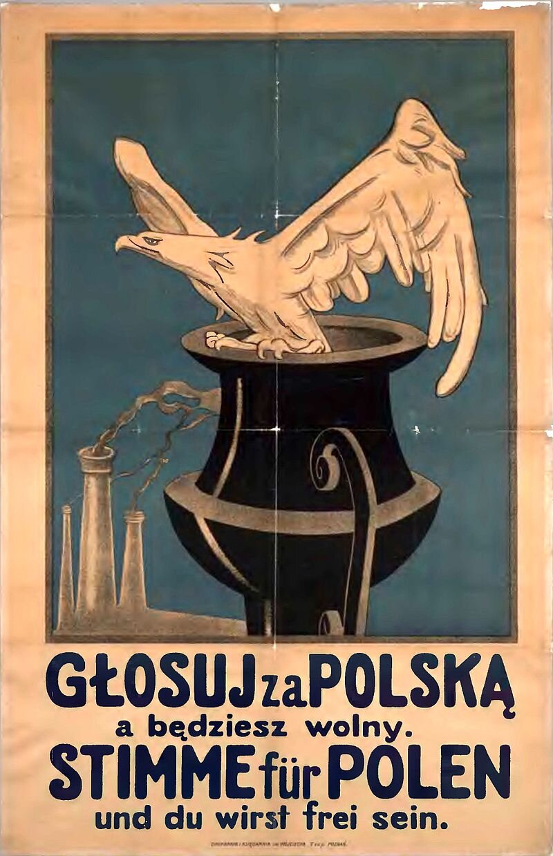 Ilustracja przedstawia plakat. Na obrzeżu czarnego kotła siedzi złoty orzeł. W tle są dymiące kominy fabryk na czystym niebieskim niebie.