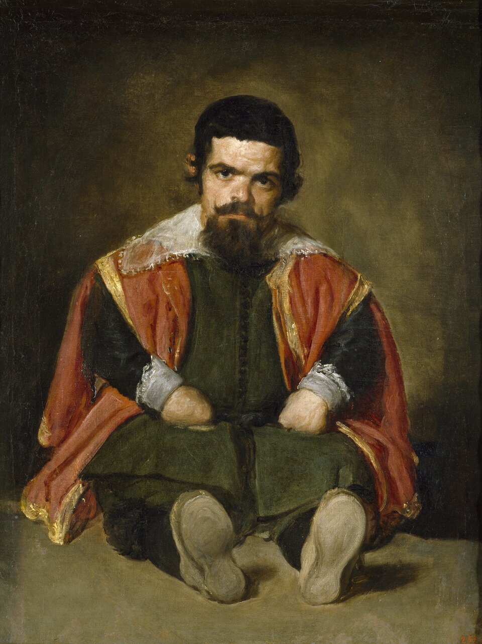 Ilustracja przedstawia portret „Don Sebastian de Morra” Diego Velázqueza. Ukazuje siedzącego na ziemi karła. Mężczyzna ubrany jest w zielone szaty oraz pomarańczową pelerynę z białym, koronkowym kołnierzem. Patrzy w stronę widza, a jego spojrzenie jest surowe. Ma czarne włosy, brodę i podkręcone wąsy. Krótkie ręce o zaciśniętych pięściach opiera na udach. Tłem jest ściana o ciemnozielonej barwie, rozjaśniona wokół postaci.