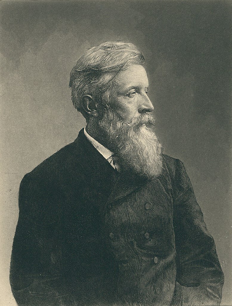 Zdjęcie przedstawia portret dojrzałego mężczyzny. Postać ukazuje prawy profil. Jego twarz jest pociągła. Oczy głęboko osadzone, nos szczupły, duży. Mężczyzna ma długą brodę i przystrzyżone wąsy. Jego włosy są półdługie i zaczesane do góry. Ubrany jest w koszulę i surdut.