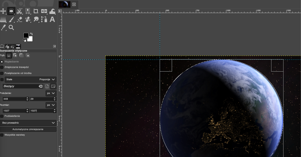 Ilustracja przedstawia wycinek okna w programie GIMP. Okno ma kolor szary, na górze i z lewej strony znajduje się podziałka z liczbami. Wewnątrz okna znajduje się fragment fotografii: kuli ziemskiej na tle gwiaździstego nieba. Na tle fotografii krzyżują się dwie przerywane, niebieskie linie – pozioma i pionowa. Kula ziemska jest wpisana w okrąg oraz w kwadrat utworzony z białych, przerywanych linii. Boki kwadratu są przedłużeniem niebieskich linii. 