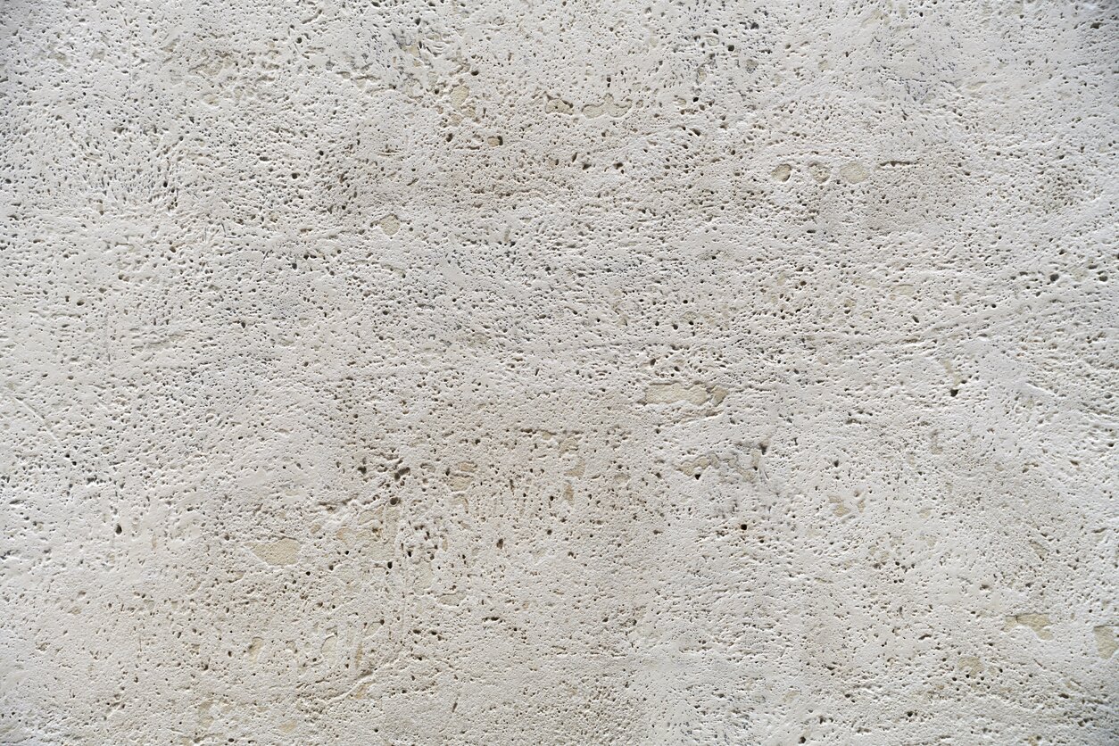 Zdjęcie przedstawia fakturę wapienia. Materiał o kremowej barwie ma porowatą strukturę, przez co na ilustracji widoczne są liczne pustki i przestrzenie między ziarnami.