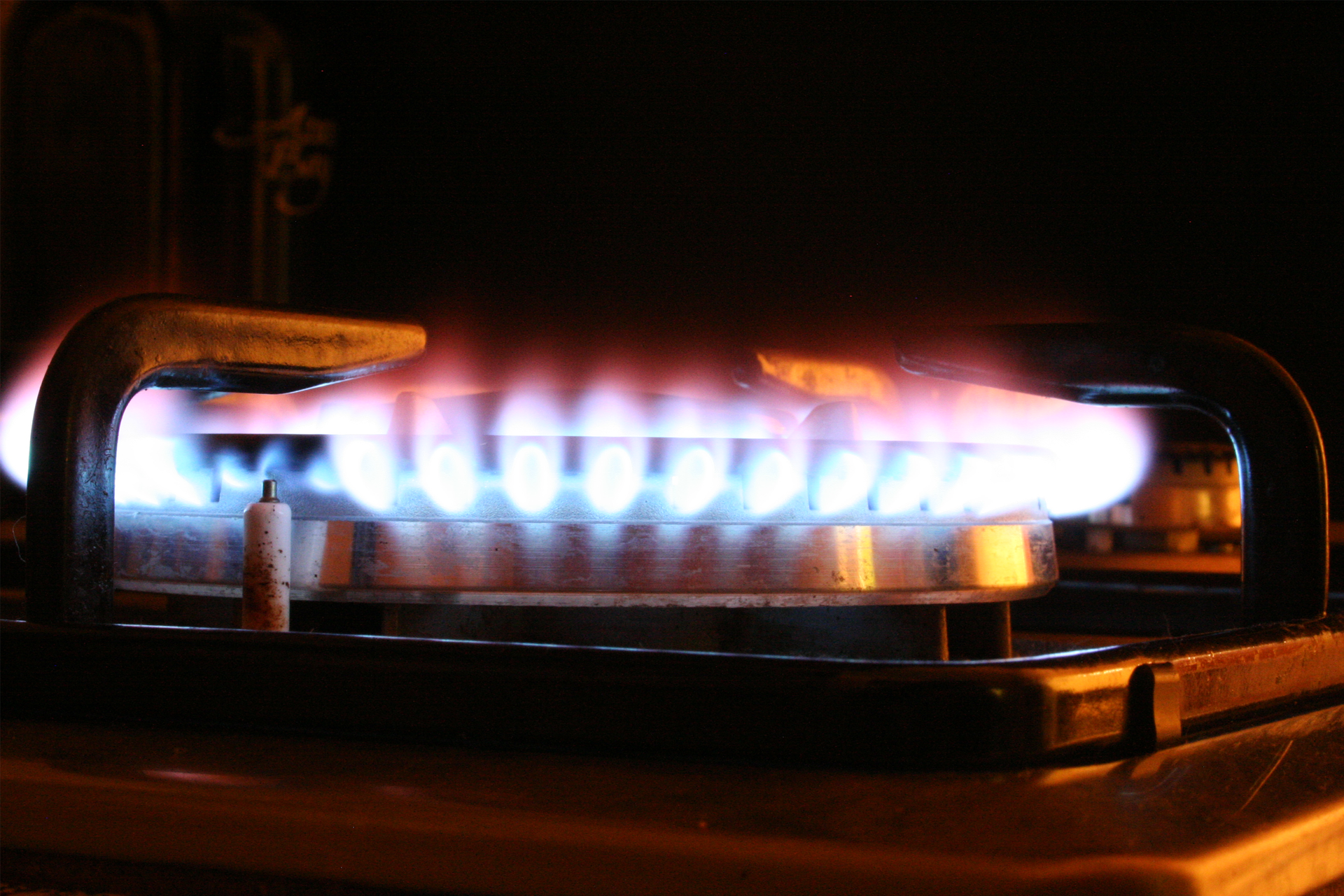 Zdjęcie przedstawia palnik kuchenny z charakterystycznym błękitnym płomieniem, na którym stoi garnek.