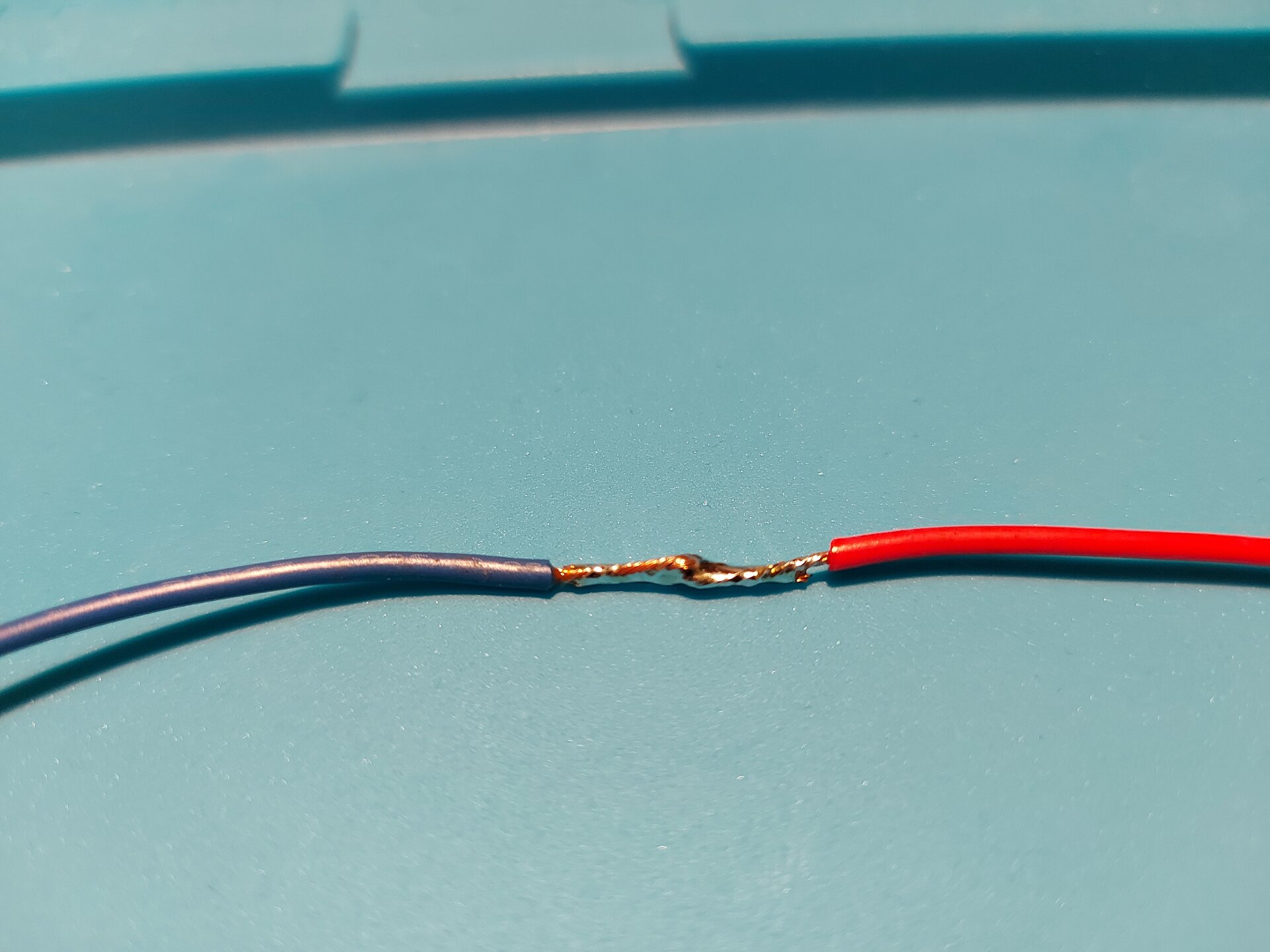 Zdjęcie przedstawia 2 przewody z usuniętą izolacją tym samym odsłaniając miedziane wnętrze, które po wygięciu w haczyki skręcono ze sobą i zlutowano.