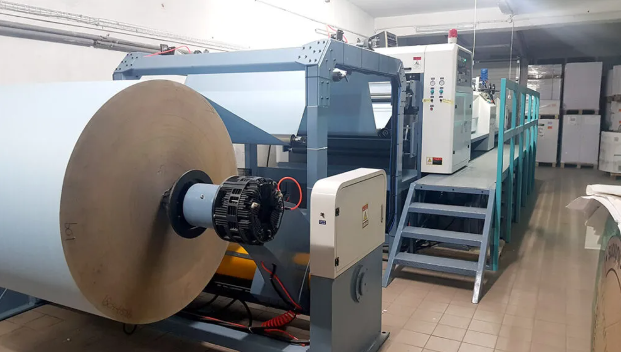 Zdjęcie ukazuje przekrawacz papieru. Jest to urządzenie wyposażone w walce, na które nawija się wstęgi papieru oraz system odpowiedzialny za jego rozcinanie.