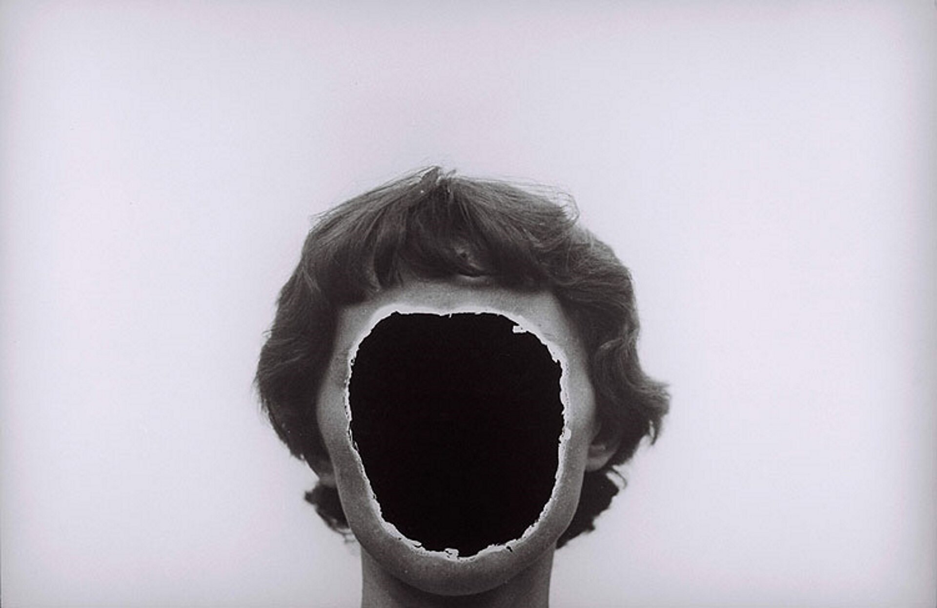 Fotografia wykonana przez Zdzisława Beksińskiego przedstawia portret żony. Kadr obejmuje tylko głowę i szyję. Lekko falowane, ciemne włosy okalają twarz, zwróconą na wprost. Zamiast oczu, nosa i ust jest wielka, jakby wycięta ostrym narzędziem dziura. Środek wypełnia czerń.  