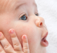 Zdjęcie przedstawia twarz malutkiego dziecka ze zdziwioną miną.