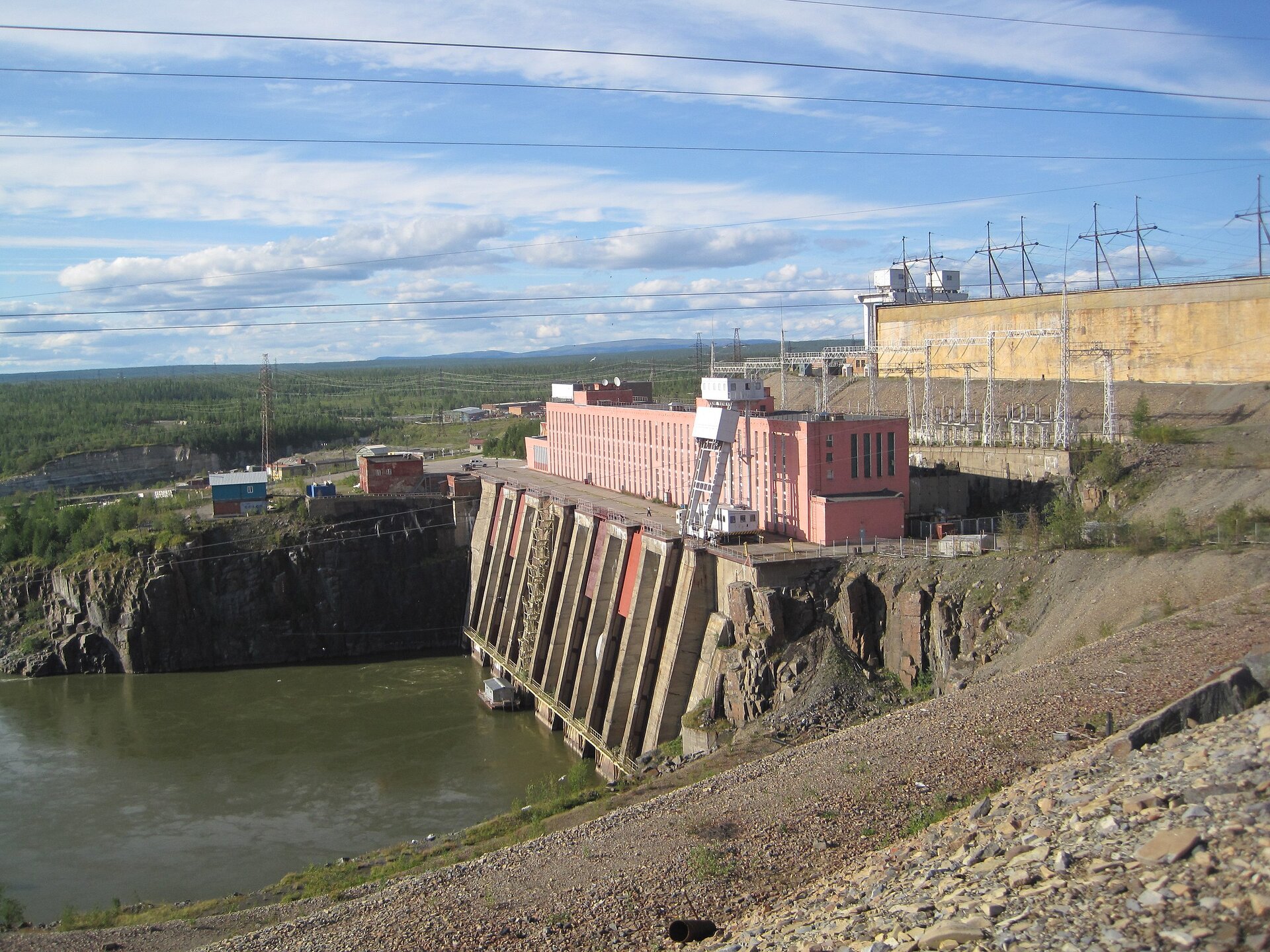 Na zdjęciu zapora na rzece, obok której zbudowane są budynki.
