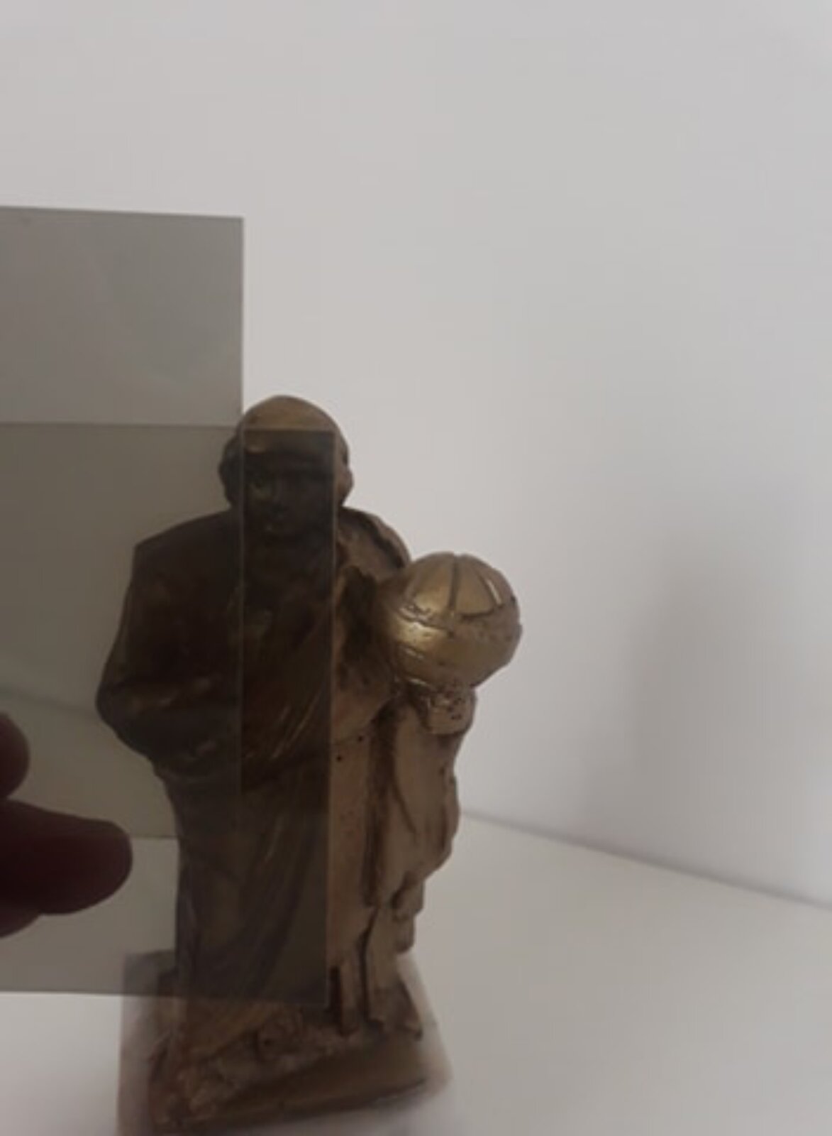 Rysunek A przedstawia wizerunek Mikołaja Kopernika oglądany przez dwa polaryzatory ustawione równolegle. Widać fragment figury odlanej z brązu na tle szarej ściany. Światło spolaryzowane przez pierwszy polaryzator przechodzi w całości przez drugi polaryzator. Do obserwatora dociera światło o mniejszym natężeniu z lewej strony z uwagi na to, że przeszło przez polaryzatory. Oglądany obraz jest w związku z tym ciemniejszy.