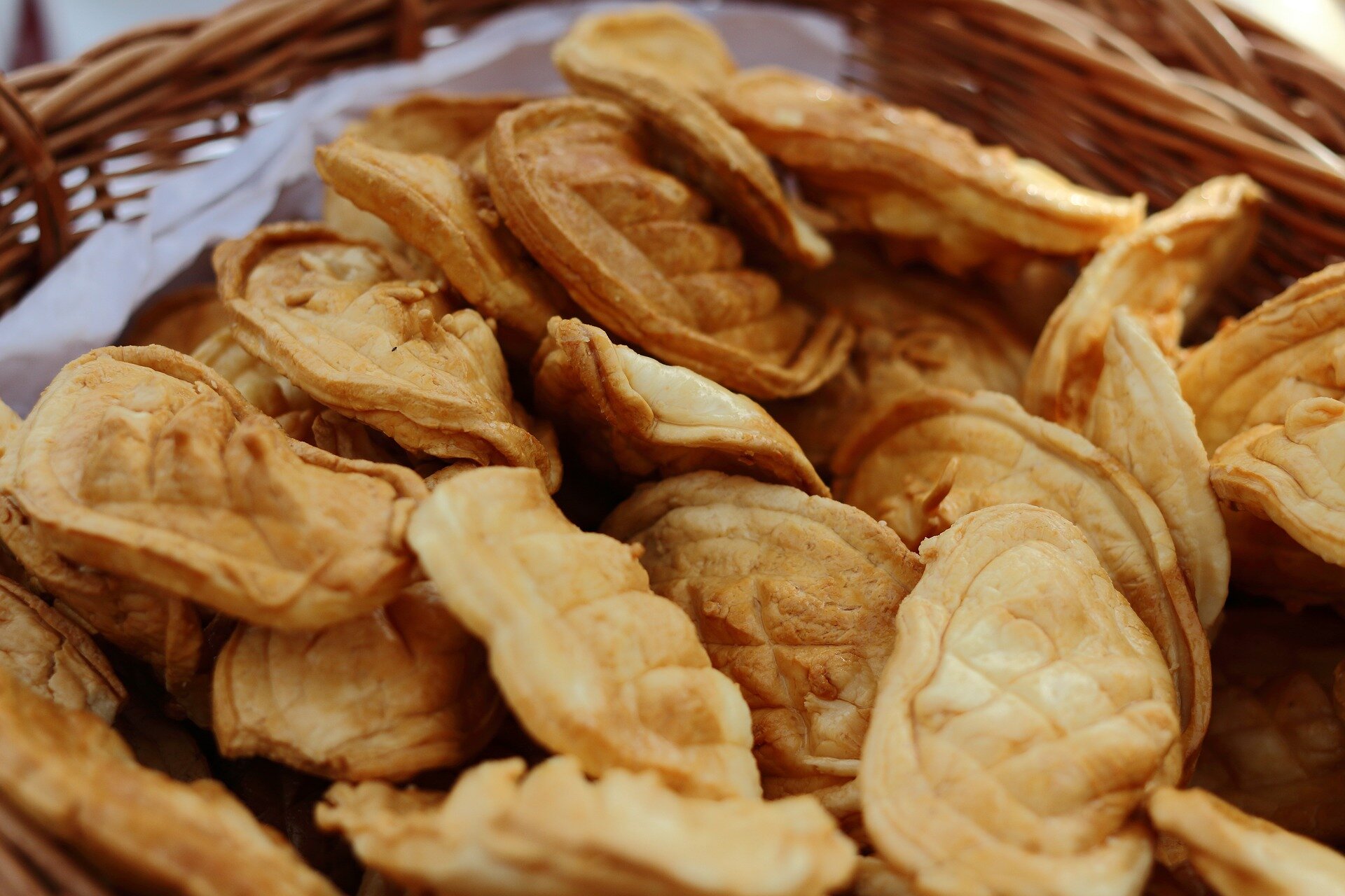 Oscypki leżące w plecionym koszyku wyłożonym białą chustą. Niewielkie kawałki serów, mające po kilka centymetrów długości, jasnobrązowego koloru.